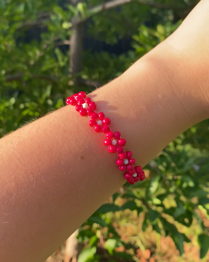 Red beaded bracelet on a wrist with a blurred natural background